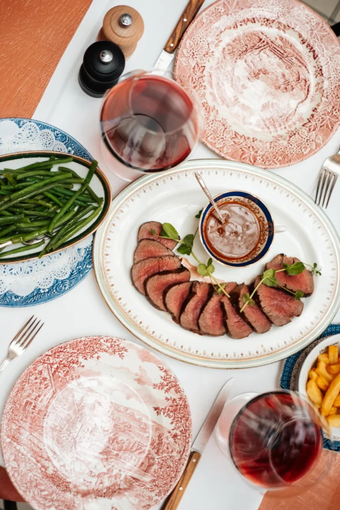 Mals gebakken steaks met friet en knapperige haricots verts, geserveerd op een wit tafelkleed bij Brasserie Bellevue, hét adres voor authentieke brasserie gerechten in Eindhoven.